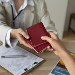Pessoa entregando um passaporte para outra.